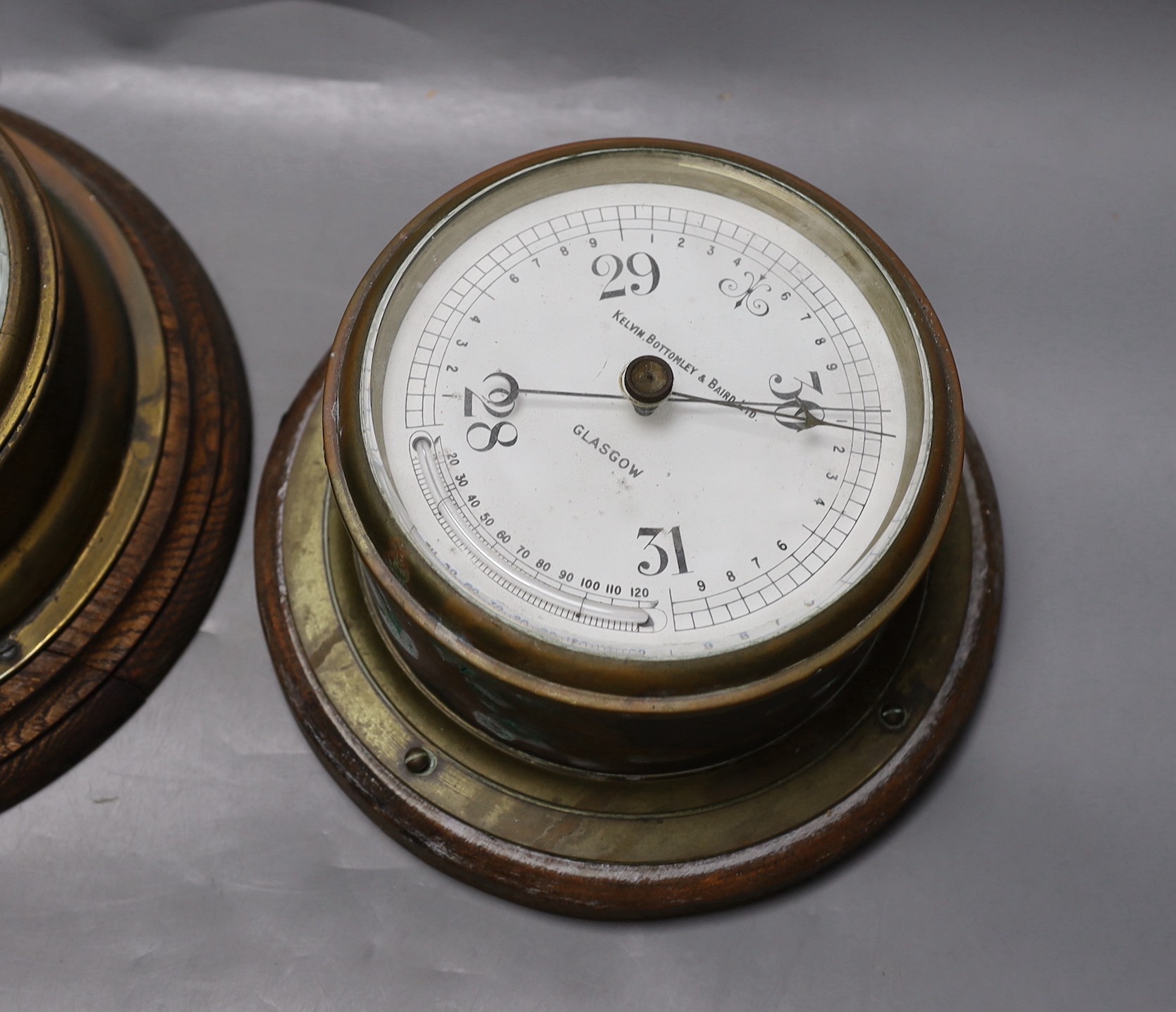 A John Barker & co brass bulkhead barometer and another by Kelvin Bottomly & Baird ltd., diameter 27. 5 cm